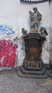 An elegant Christian statue next to rough Graffiti